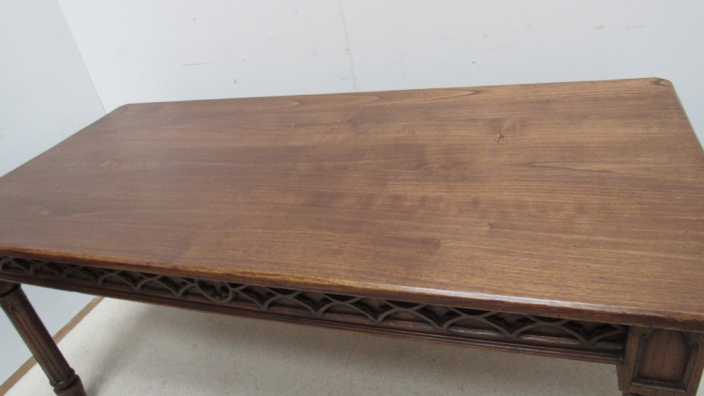 A rectangular solid oak refectory table featuring carved Gothic blind tracery along the frieze and turned column legs. View II