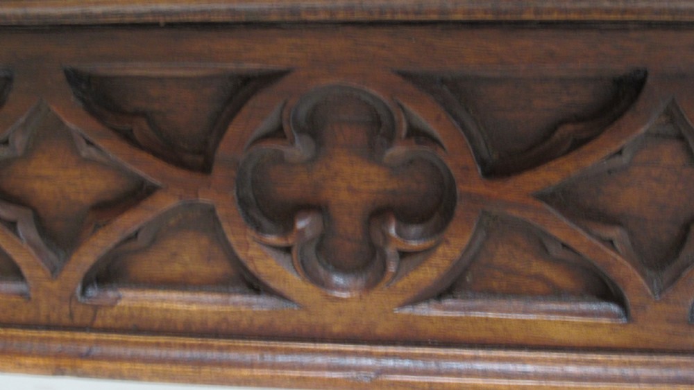 A rectangular solid oak refectory table featuring carved Gothic blind tracery along the frieze and turned column legs. View III