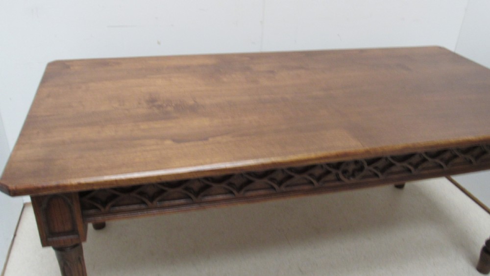 A rectangular solid oak refectory table featuring carved Gothic blind tracery along the frieze and turned column legs. View IX