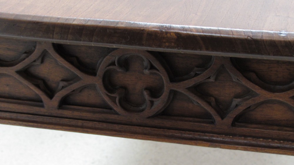 A rectangular solid oak refectory table featuring carved Gothic blind tracery along the frieze and turned column legs. View XI