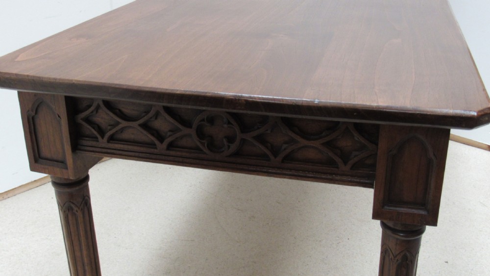 A rectangular solid oak refectory table featuring carved Gothic blind tracery along the frieze and turned column legs. View XII