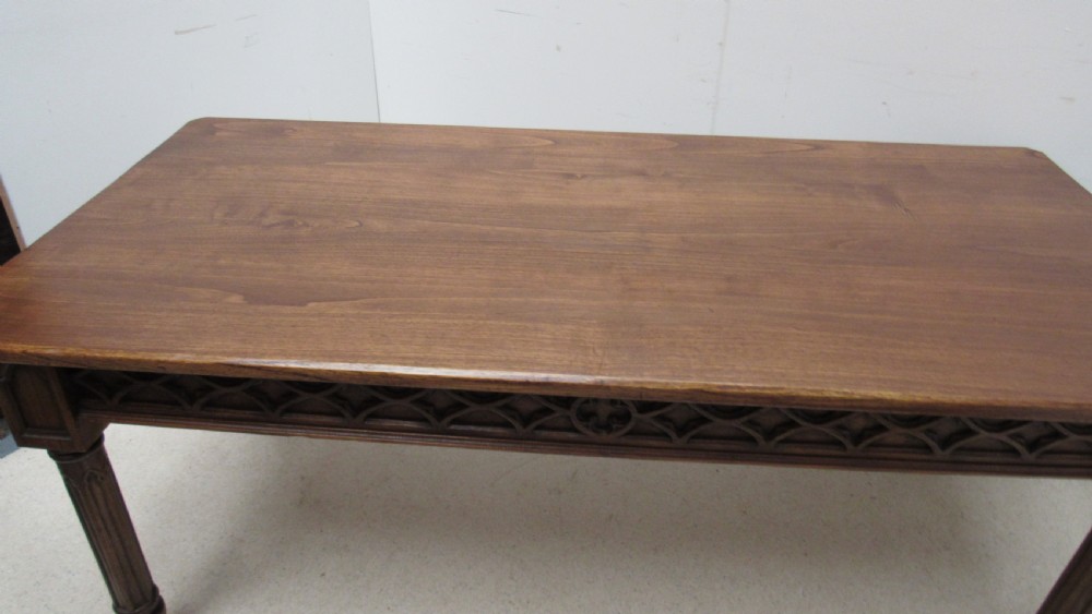 A rectangular solid oak refectory table featuring carved Gothic blind tracery along the frieze and turned column legs. View XIII