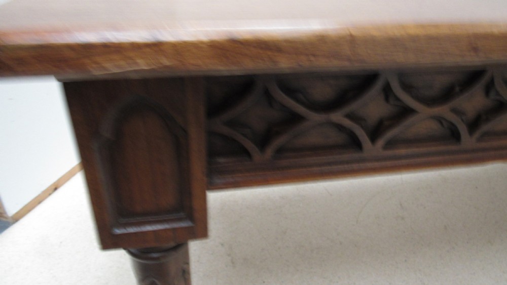 A rectangular solid oak refectory table featuring carved Gothic blind tracery along the frieze and turned column legs. View XV
