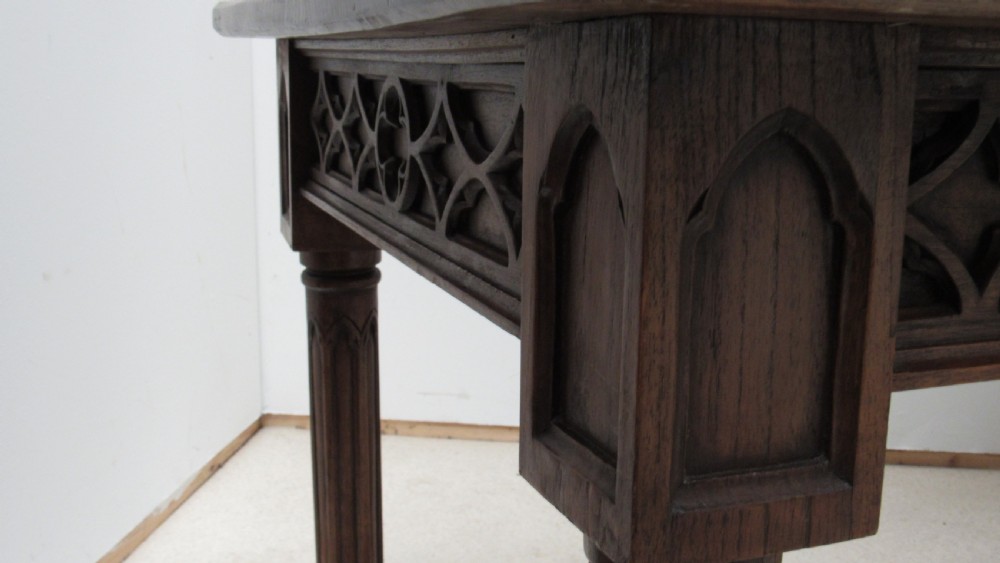 A rectangular solid oak refectory table featuring carved Gothic blind tracery along the frieze and turned column legs. View XVII