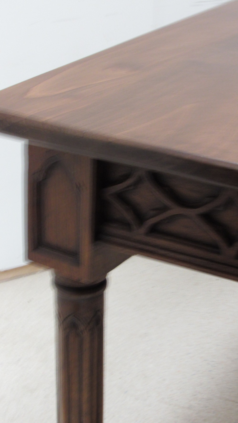 A rectangular solid oak refectory table featuring carved Gothic blind tracery along the frieze and turned column legs. View XXI