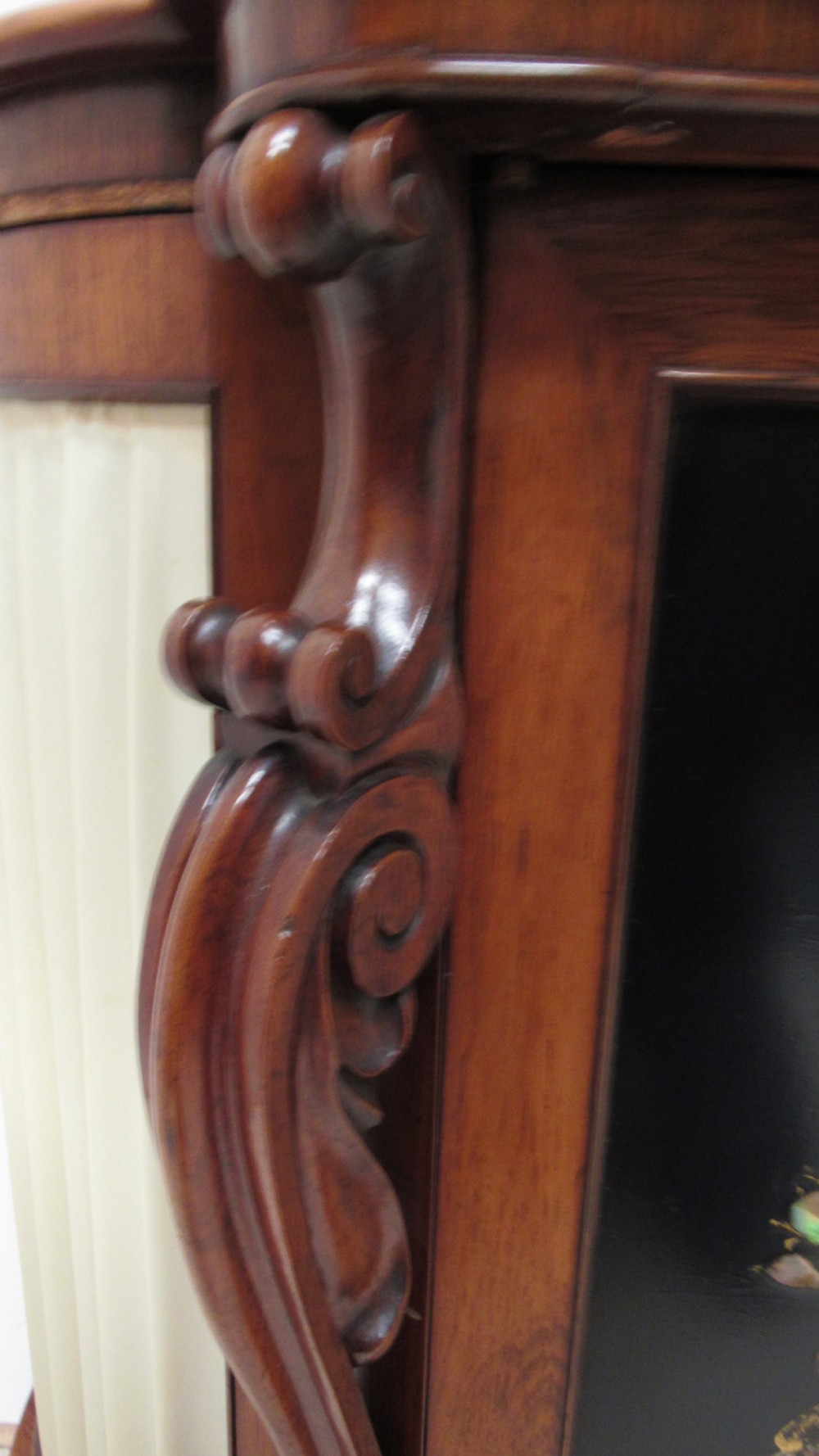 A nineteenth-century dark wood side cabinet featuring two central black door panels decorated with floral arrangements, framed by carved scroll supports and curved pleated side sections. View V
