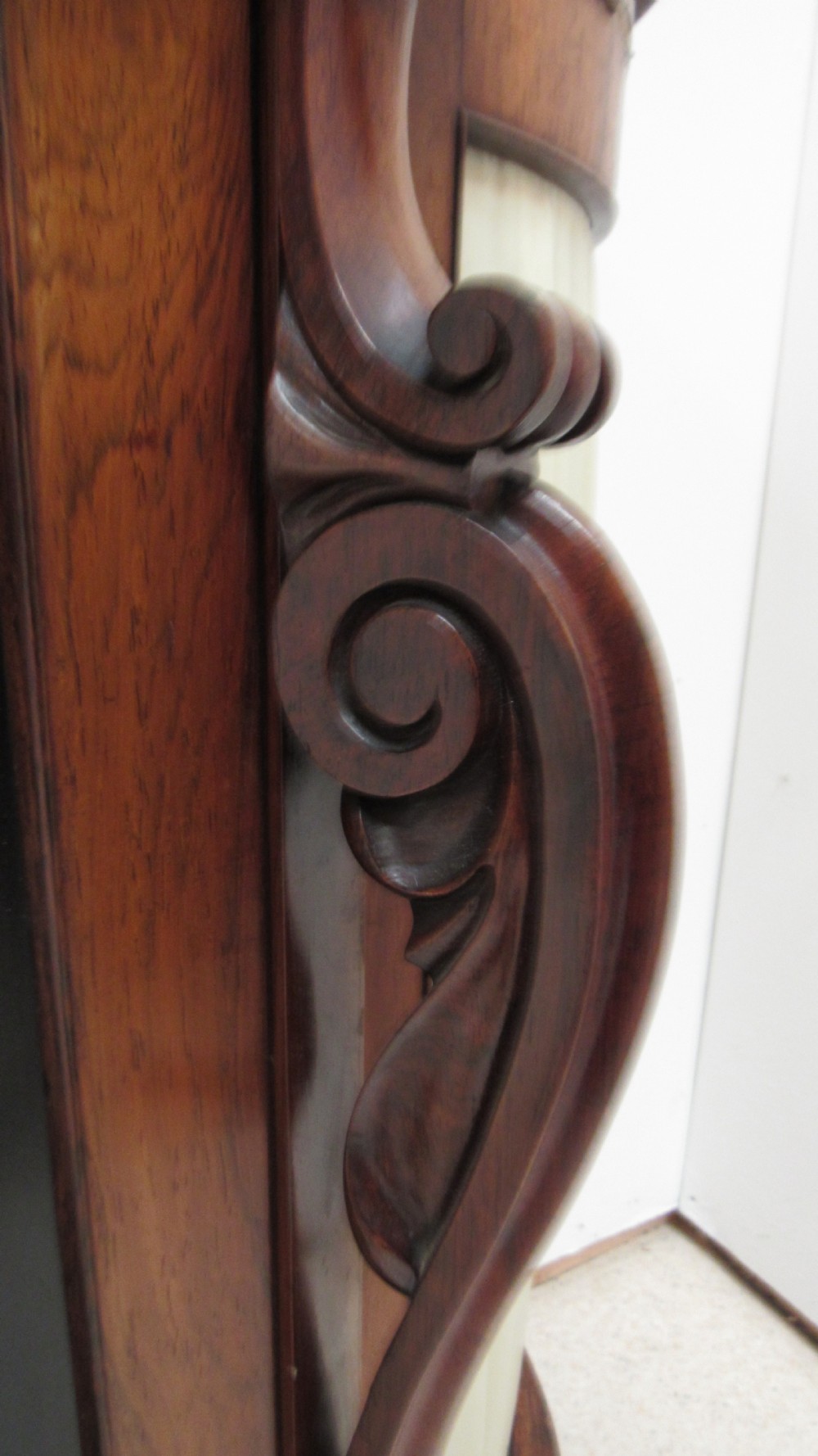 A nineteenth-century dark wood side cabinet featuring two central black door panels decorated with floral arrangements, framed by carved scroll supports and curved pleated side sections. View VI