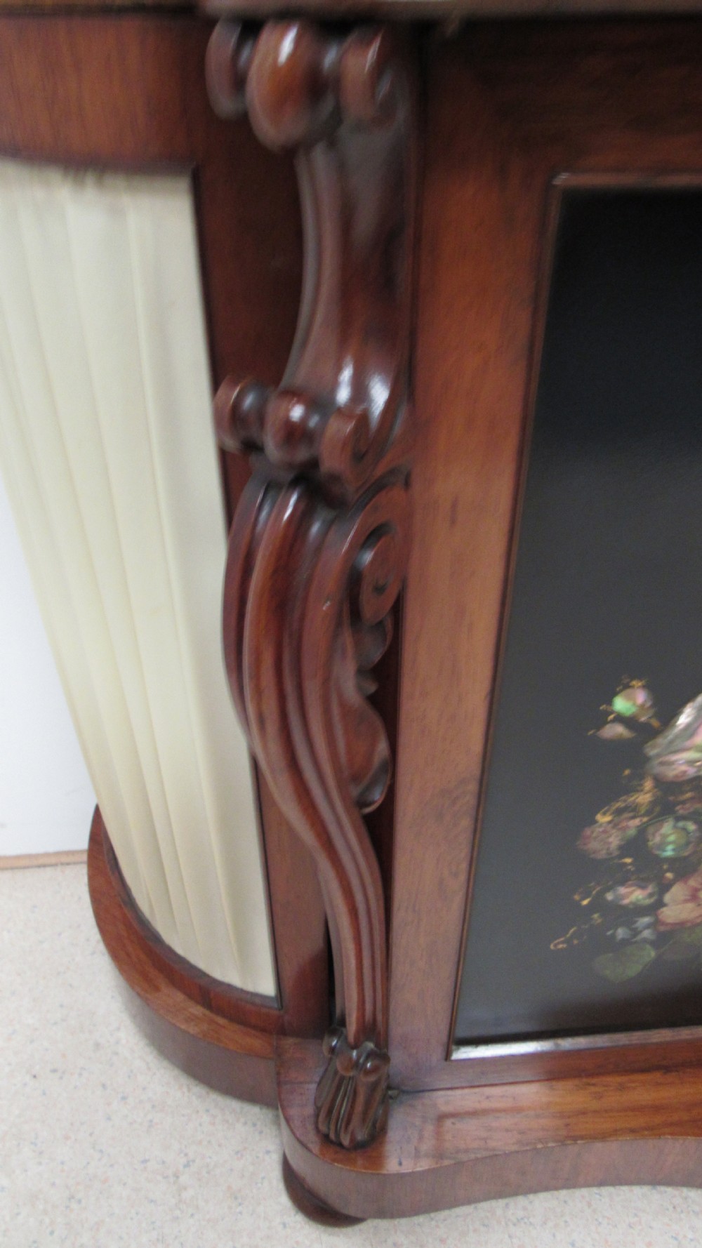 A nineteenth-century dark wood side cabinet featuring two central black door panels decorated with floral arrangements, framed by carved scroll supports and curved pleated side sections. View IX