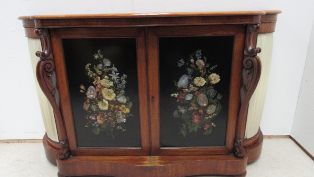 A nineteenth-century dark wood side cabinet featuring two central black door panels decorated with floral arrangements, framed by carved scroll supports and curved pleated side sections. View X