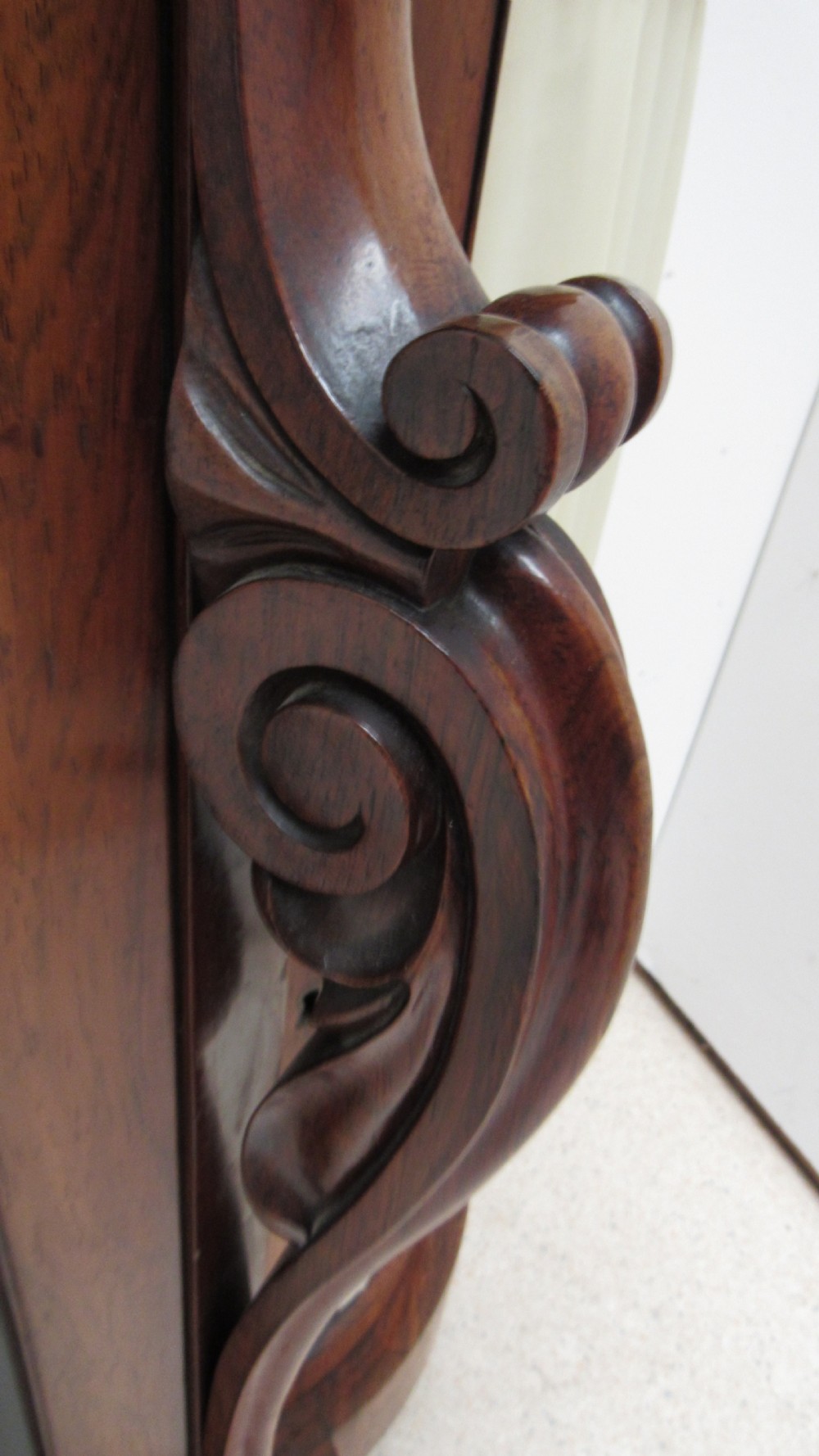 A nineteenth-century dark wood side cabinet featuring two central black door panels decorated with floral arrangements, framed by carved scroll supports and curved pleated side sections. View XII