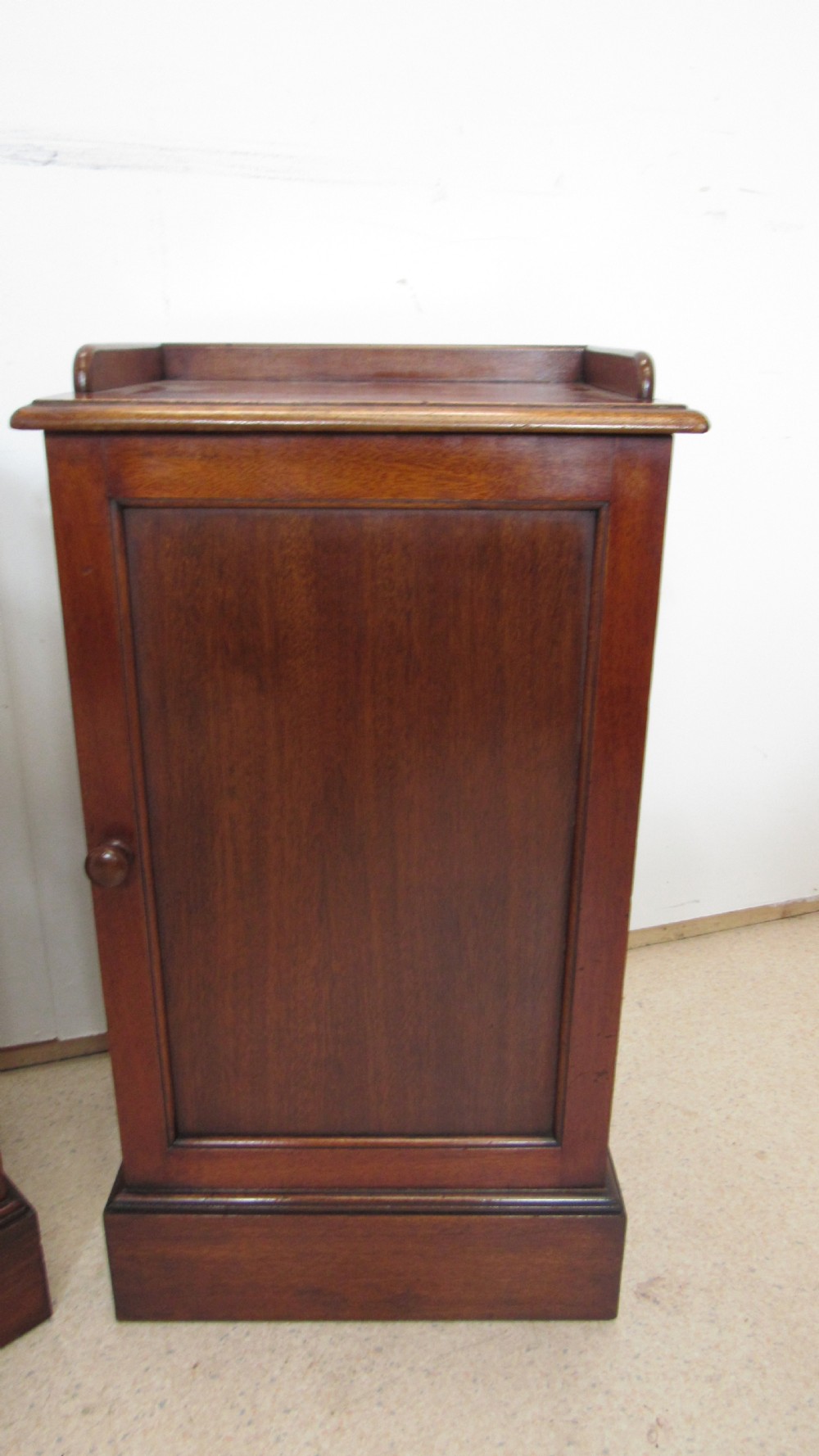 A pair of antique mahogany pot cupboards featuring three-sided gallery tops, single panelled doors with wooden knobs, and solid plinth bases. View II