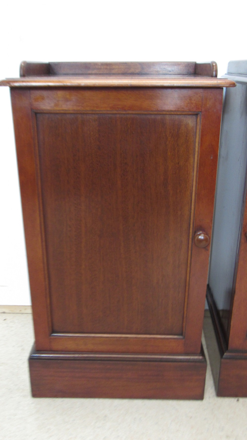 A pair of antique mahogany pot cupboards featuring three-sided gallery tops, single panelled doors with wooden knobs, and solid plinth bases. View VI