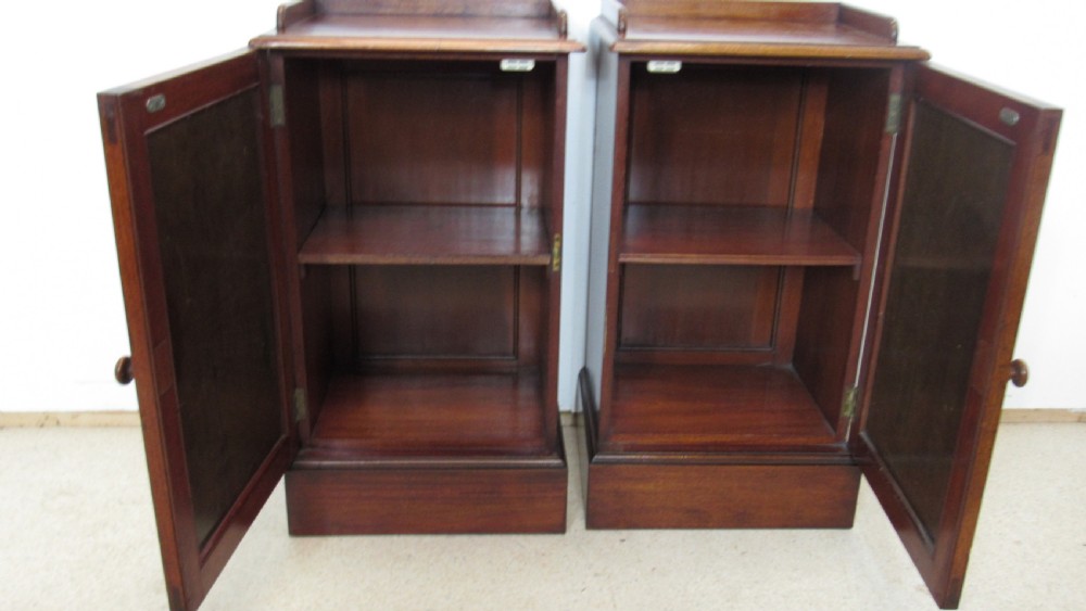 A pair of antique mahogany pot cupboards featuring three-sided gallery tops, single panelled doors with wooden knobs, and solid plinth bases. View VII