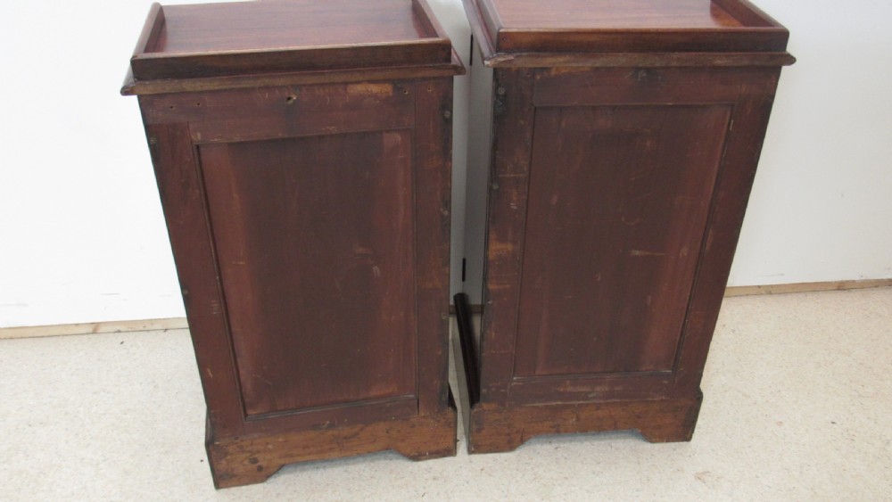 A pair of antique mahogany pot cupboards featuring three-sided gallery tops, single panelled doors with wooden knobs, and solid plinth bases. View XV