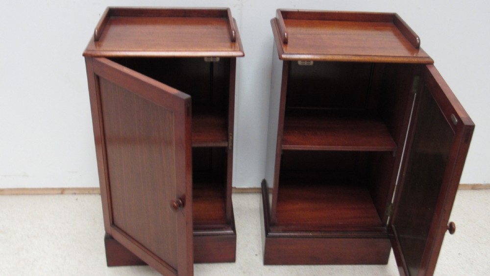 A pair of antique mahogany pot cupboards featuring three-sided gallery tops, single panelled doors with wooden knobs, and solid plinth bases. View XVIII