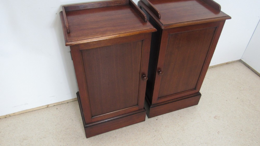 A pair of antique mahogany pot cupboards featuring three-sided gallery tops, single panelled doors with wooden knobs, and solid plinth bases. View XIX