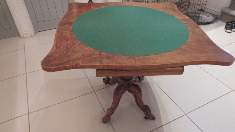 An antique Victorian walnut card table featuring a serpentine fold-over top resting on a carved central pedestal and scroll feet. View XI