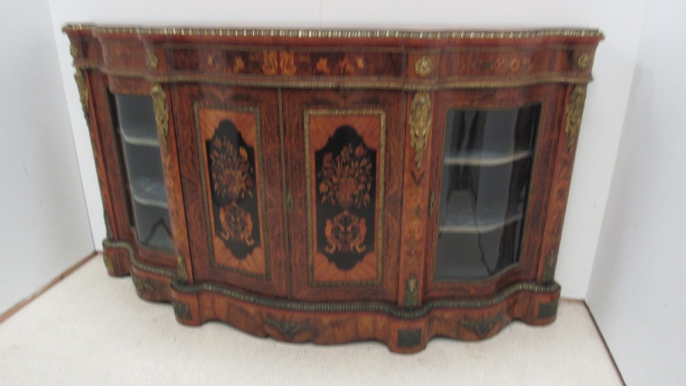 A Victorian serpentine-front credenza featuring central floral marquetry doors, glass display side cupboards, and ornate gilt-bronze mounts. View IV