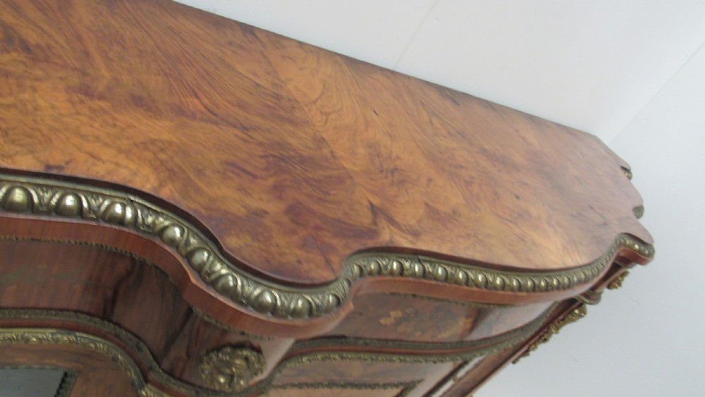 A Victorian serpentine-front credenza featuring central floral marquetry doors, glass display side cupboards, and ornate gilt-bronze mounts. View XII