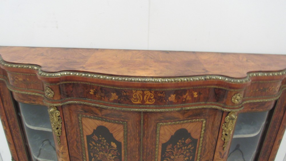 A Victorian serpentine-front credenza featuring central floral marquetry doors, glass display side cupboards, and ornate gilt-bronze mounts. View XVI