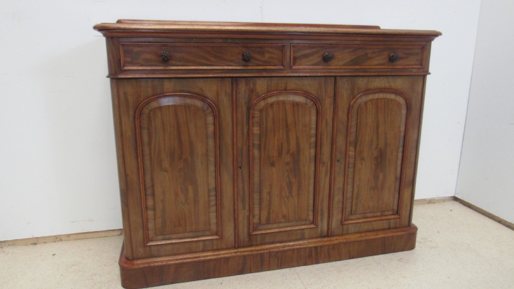 A Victorian mahogany side cabinet with a low rear gallery, two upper drawers, and three arched panel cupboard doors set on a plinth base. View II