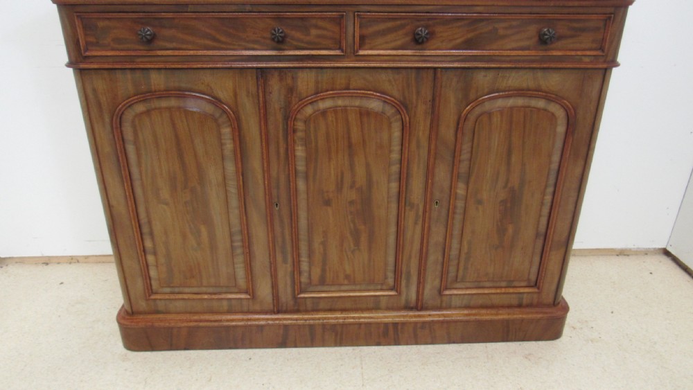 A Victorian mahogany side cabinet with a low rear gallery, two upper drawers, and three arched panel cupboard doors set on a plinth base. View XI