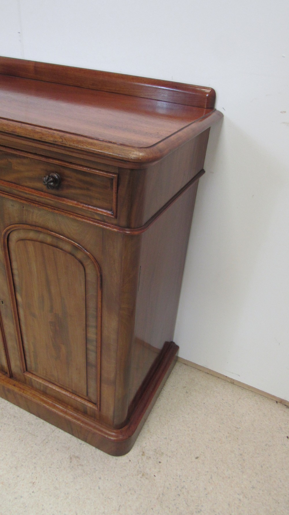 A Victorian mahogany side cabinet with a low rear gallery, two upper drawers, and three arched panel cupboard doors set on a plinth base. View XIV