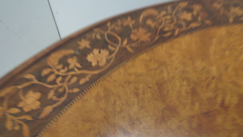 A circular Victorian walnut occasional table featuring intricate floral marquetry inlay along the border and central medallion, supported on a carved tripod pedestal base. View VII