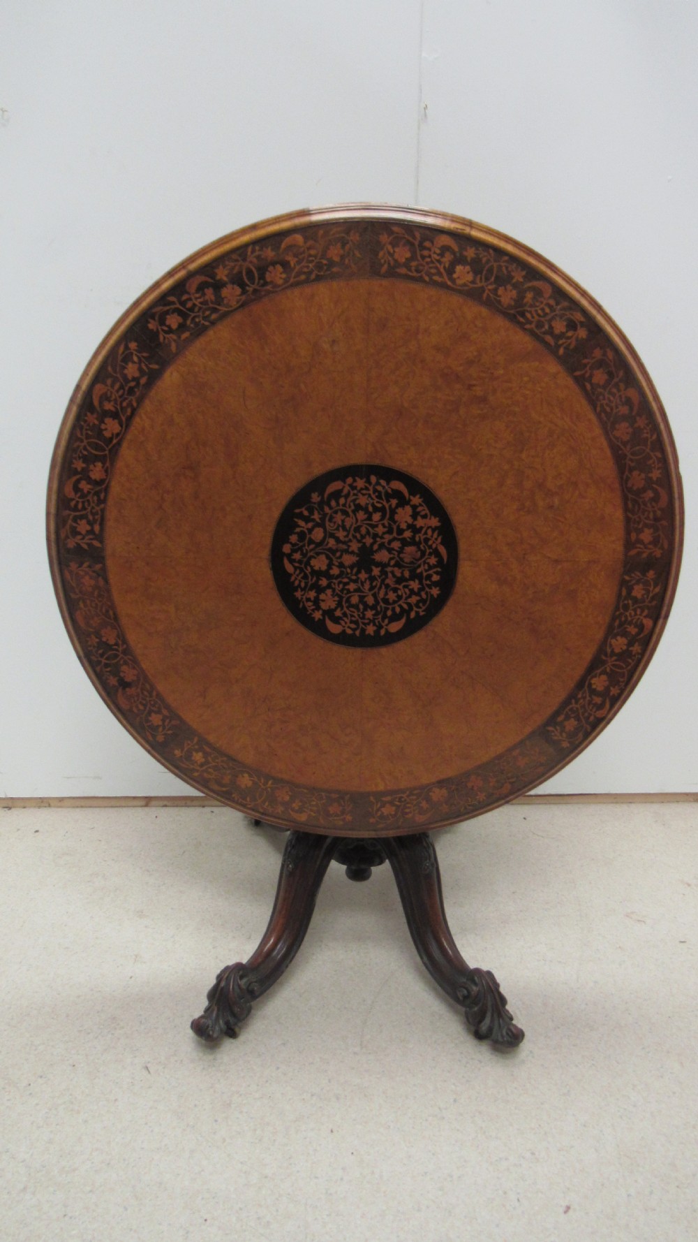 A circular Victorian walnut occasional table featuring intricate floral marquetry inlay along the border and central medallion, supported on a carved tripod pedestal base. View VIII