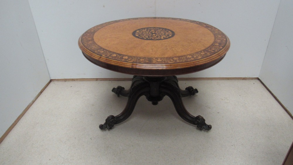 A circular Victorian walnut occasional table featuring intricate floral marquetry inlay along the border and central medallion, supported on a carved tripod pedestal base. View XVI