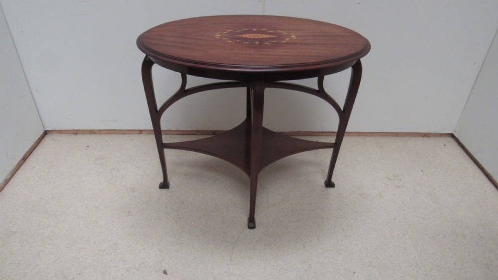 An oval dark mahogany occasional table featuring a central decorative marquetry inlay, sweeping curved legs, and a small shaped lower tier.