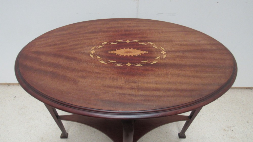 An oval dark mahogany occasional table featuring a central decorative marquetry inlay, sweeping curved legs, and a small shaped lower tier. View II