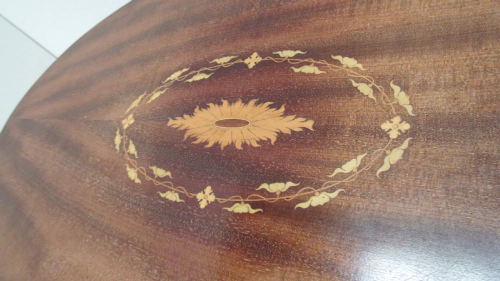 An oval dark mahogany occasional table featuring a central decorative marquetry inlay, sweeping curved legs, and a small shaped lower tier. View III