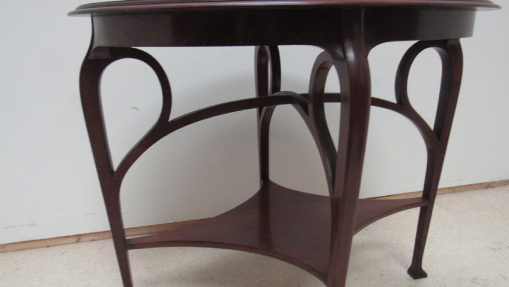 An oval dark mahogany occasional table featuring a central decorative marquetry inlay, sweeping curved legs, and a small shaped lower tier. View IV