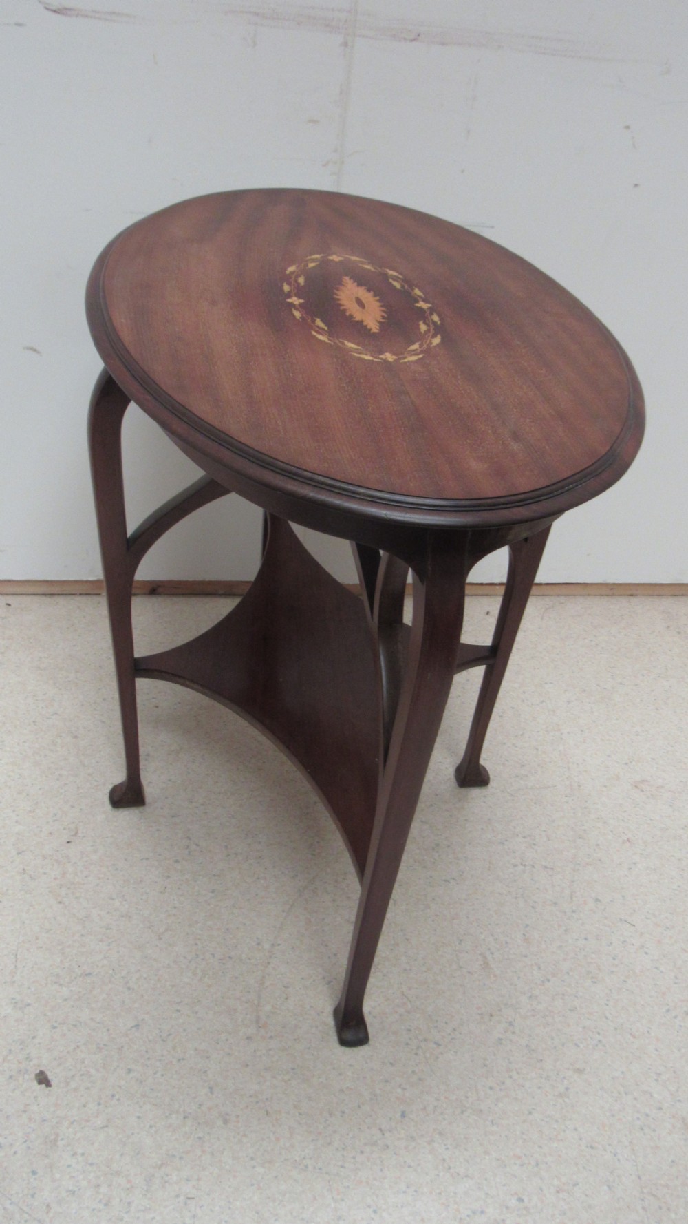 An oval dark mahogany occasional table featuring a central decorative marquetry inlay, sweeping curved legs, and a small shaped lower tier. View VII