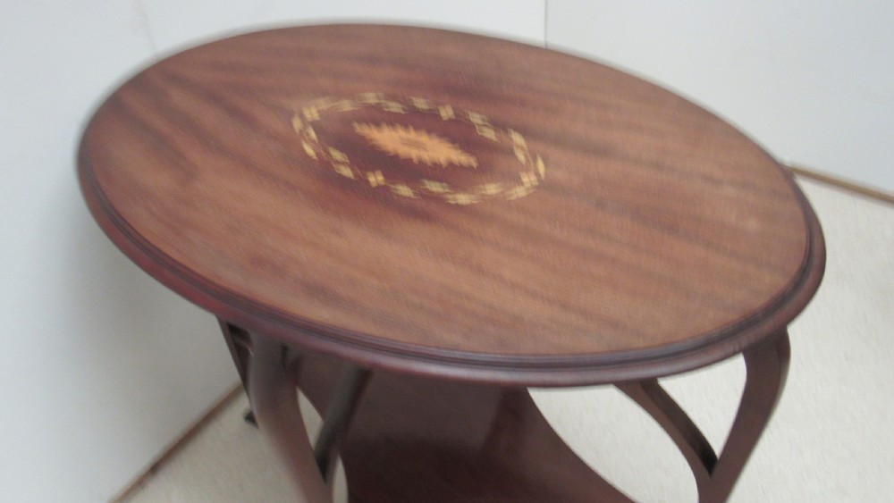 An oval dark mahogany occasional table featuring a central decorative marquetry inlay, sweeping curved legs, and a small shaped lower tier. View VIII