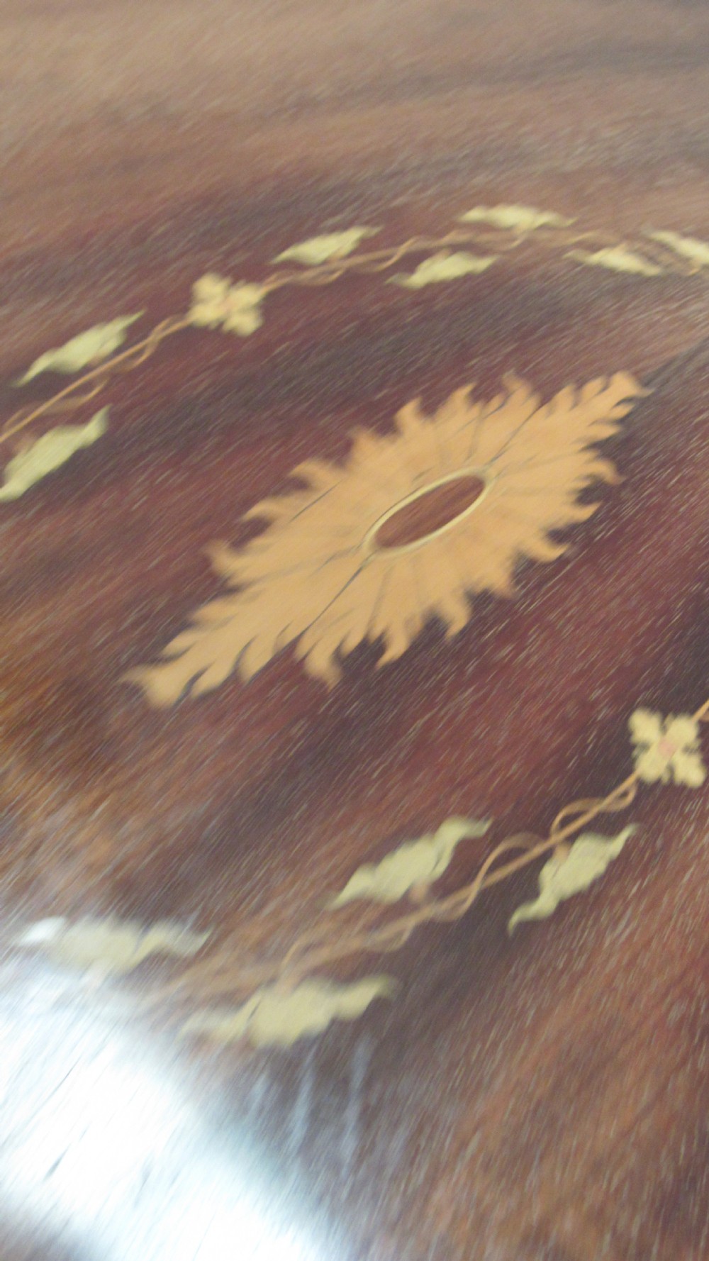 An oval dark mahogany occasional table featuring a central decorative marquetry inlay, sweeping curved legs, and a small shaped lower tier. View X