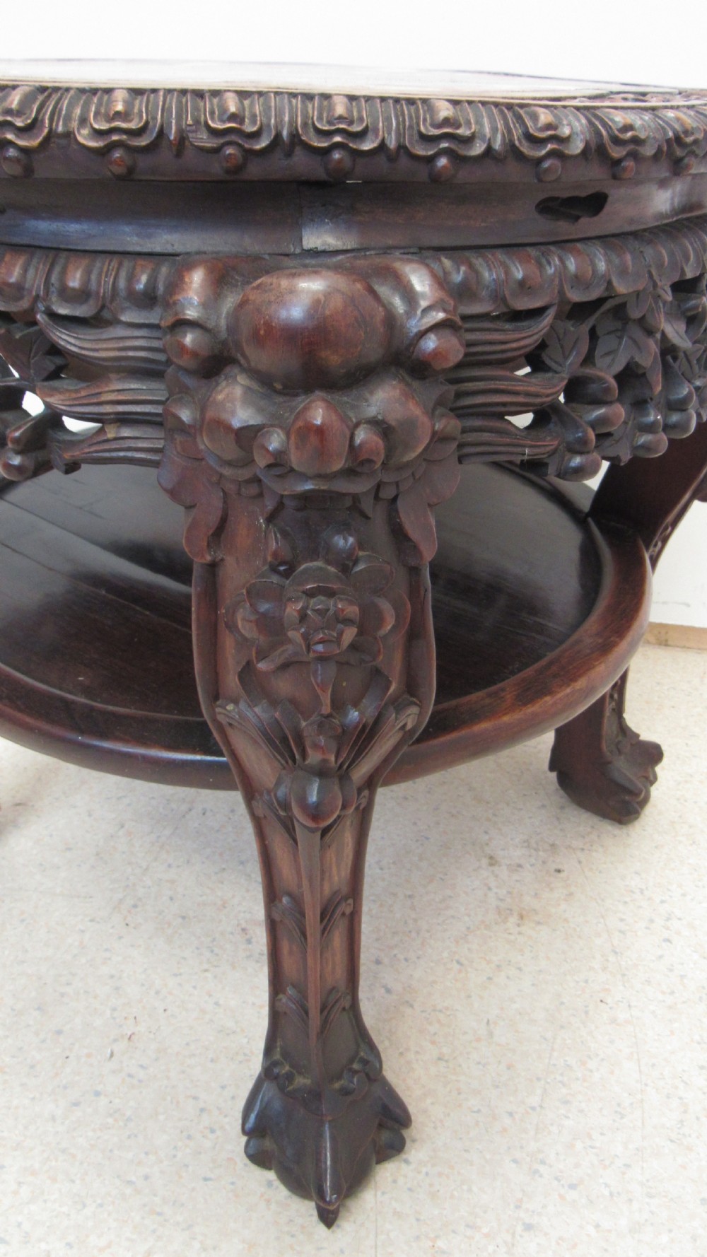 A circular dark wood urn stand featuring an inset pink marble top, detailed relief carving on the apron, curved cabriole legs, and a lower shelf. View III