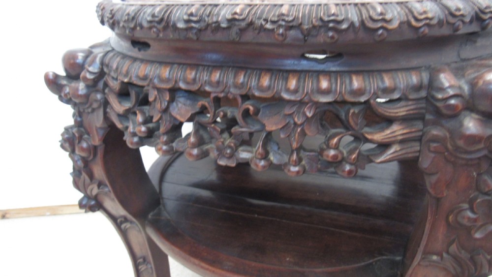A circular dark wood urn stand featuring an inset pink marble top, detailed relief carving on the apron, curved cabriole legs, and a lower shelf. View V