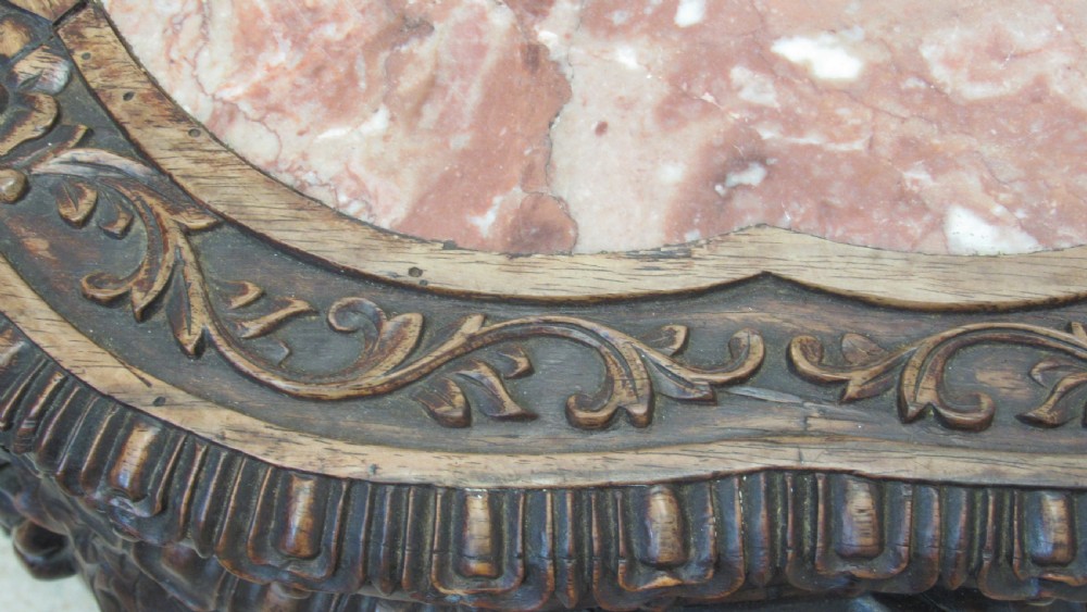 A circular dark wood urn stand featuring an inset pink marble top, detailed relief carving on the apron, curved cabriole legs, and a lower shelf. View XII