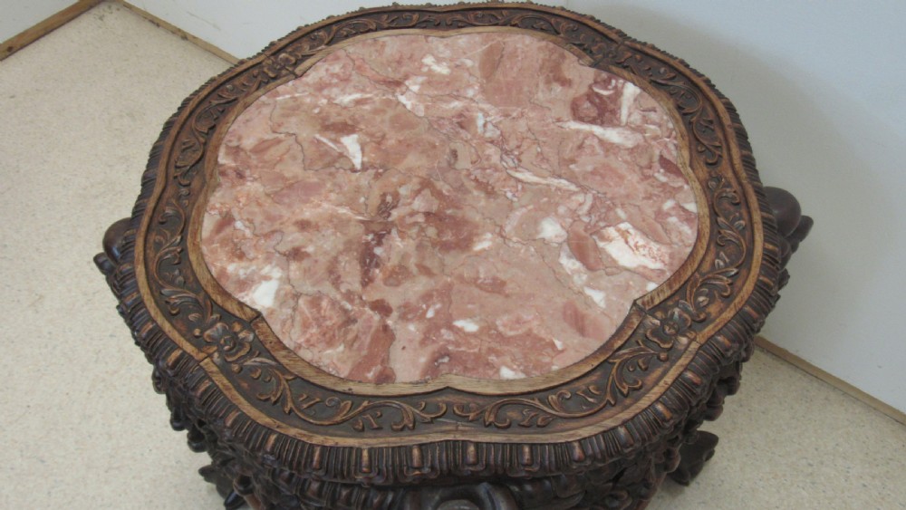 A circular dark wood urn stand featuring an inset pink marble top, detailed relief carving on the apron, curved cabriole legs, and a lower shelf. View XIII