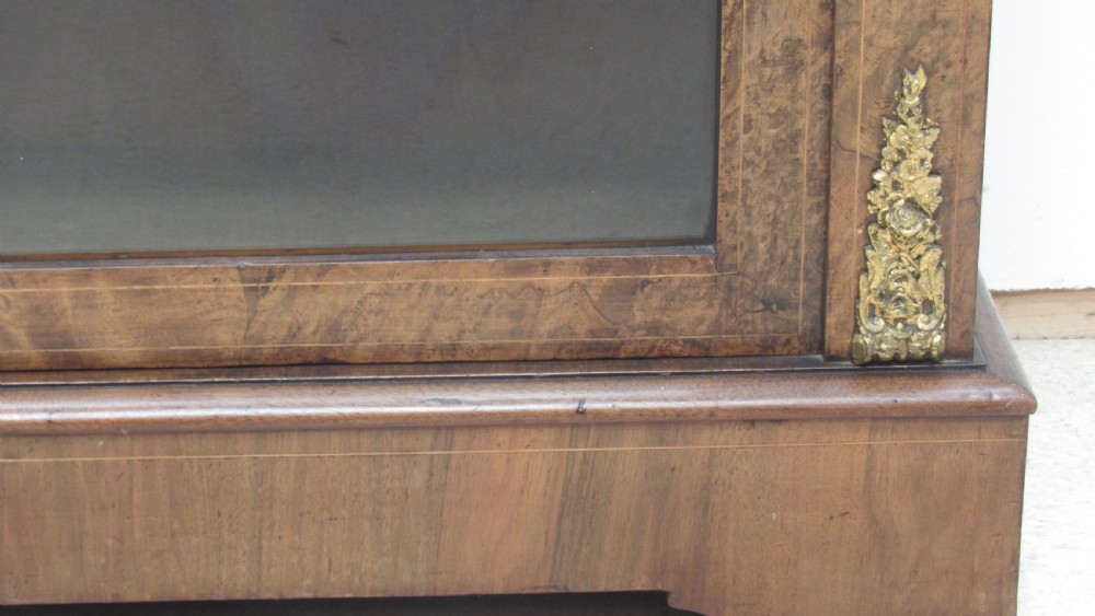 A 19th-century Victorian burr walnut pier cabinet featuring floral marquetry inlay, glazed double doors, glass shelves, and gilt brass corner mounts. View IV