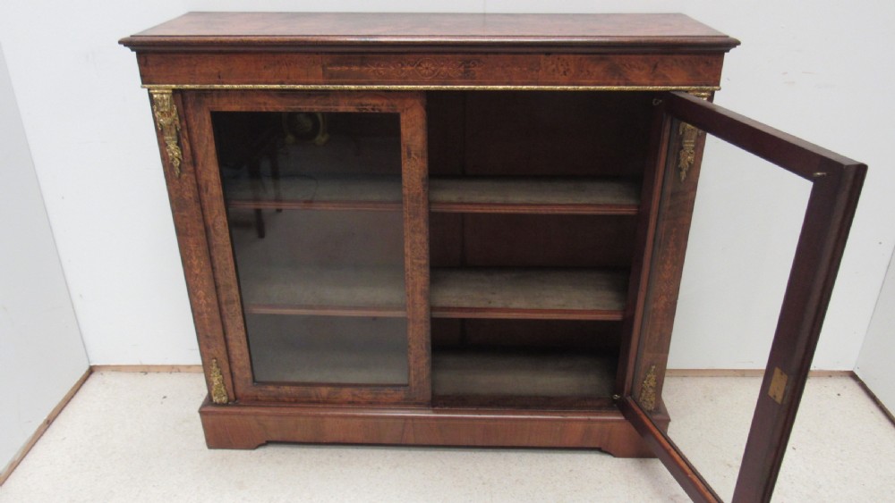 A 19th-century Victorian burr walnut pier cabinet featuring floral marquetry inlay, glazed double doors, glass shelves, and gilt brass corner mounts. View VIII