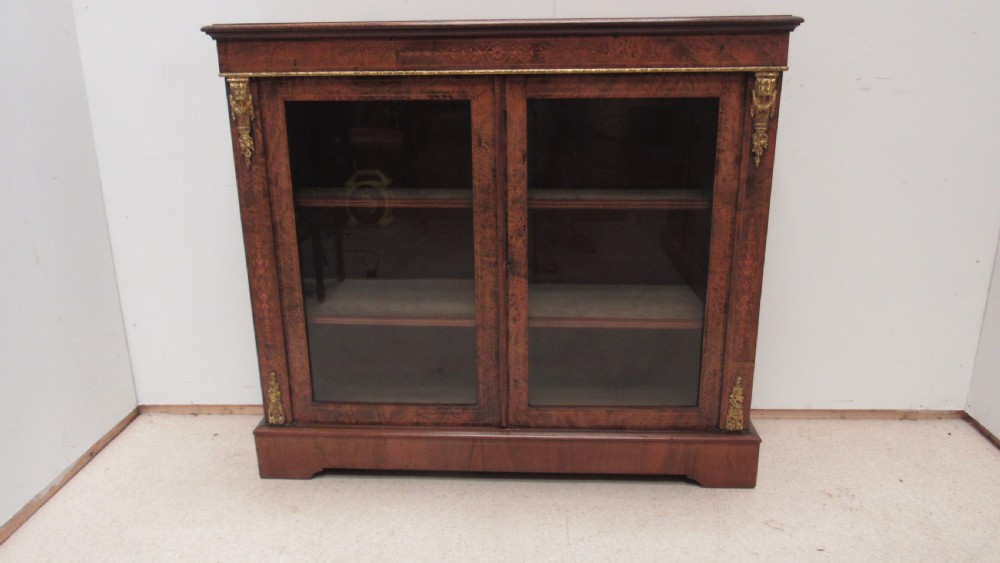 A 19th-century Victorian burr walnut pier cabinet featuring floral marquetry inlay, glazed double doors, glass shelves, and gilt brass corner mounts. View XII