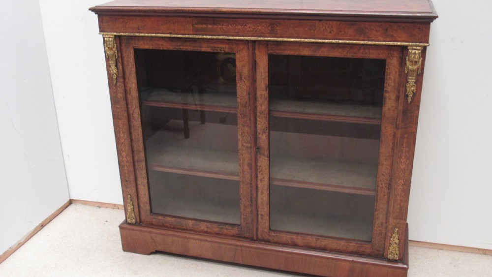A 19th-century Victorian burr walnut pier cabinet featuring floral marquetry inlay, glazed double doors, glass shelves, and gilt brass corner mounts. View XIII