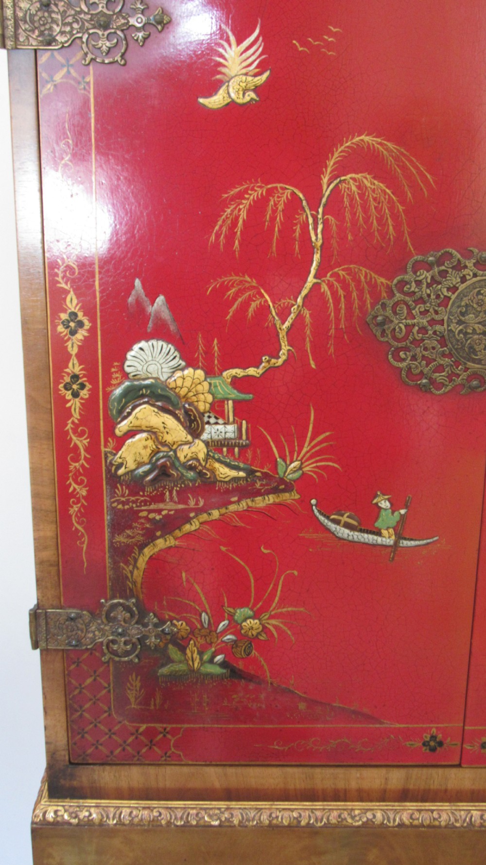 A red lacquered chinoiserie cocktail cabinet decorated with gilt landscapes and figures, featuring ornate brass hinges and set on a carved timber stand with cabriole legs. View IV