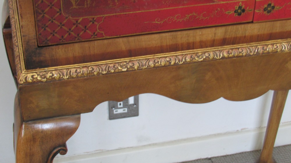 A red lacquered chinoiserie cocktail cabinet decorated with gilt landscapes and figures, featuring ornate brass hinges and set on a carved timber stand with cabriole legs. View VII