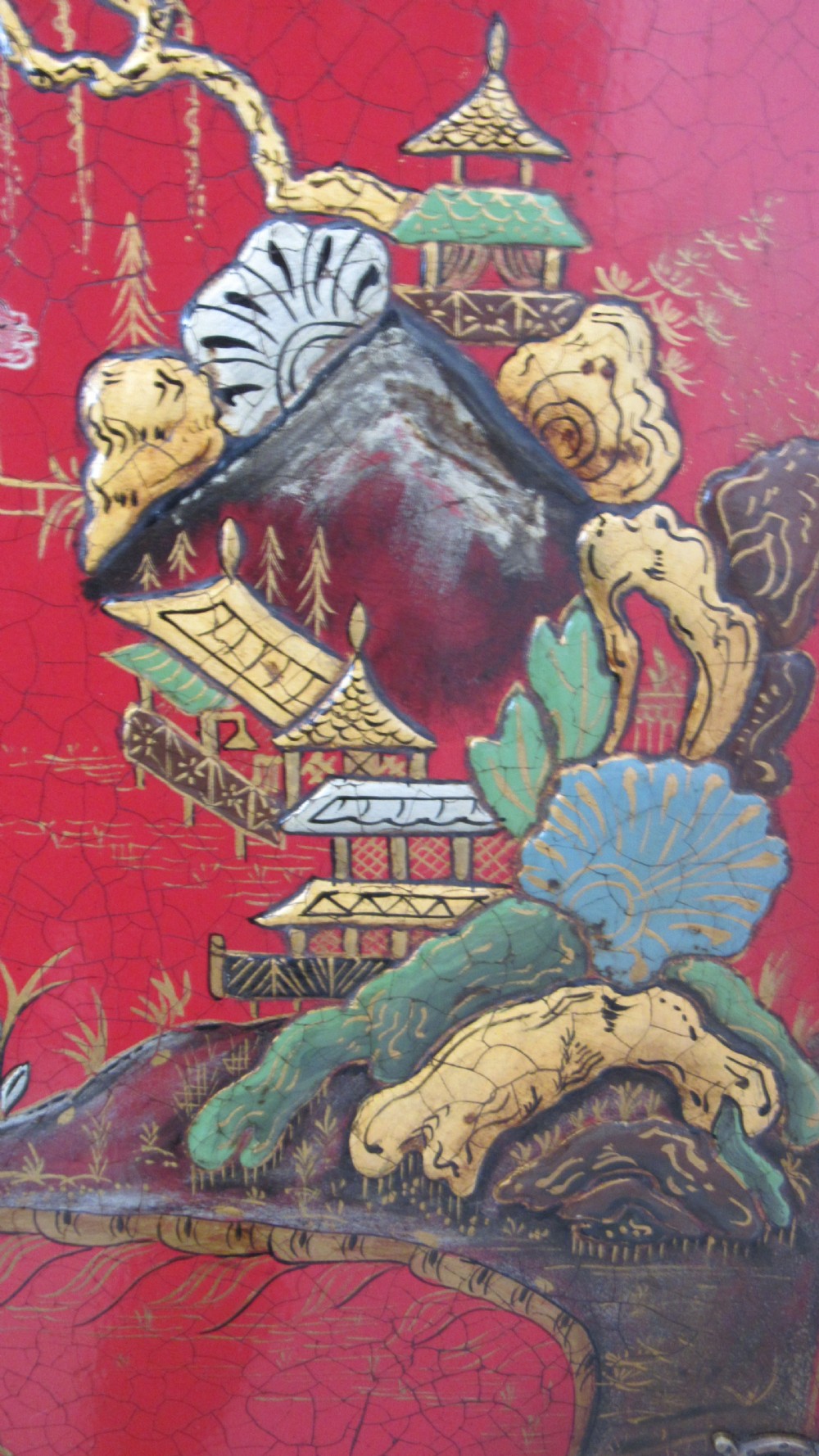 A red lacquered chinoiserie cocktail cabinet decorated with gilt landscapes and figures, featuring ornate brass hinges and set on a carved timber stand with cabriole legs. View X