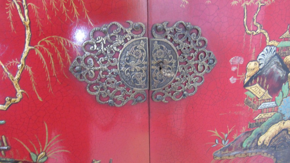 A red lacquered chinoiserie cocktail cabinet decorated with gilt landscapes and figures, featuring ornate brass hinges and set on a carved timber stand with cabriole legs. View XVI