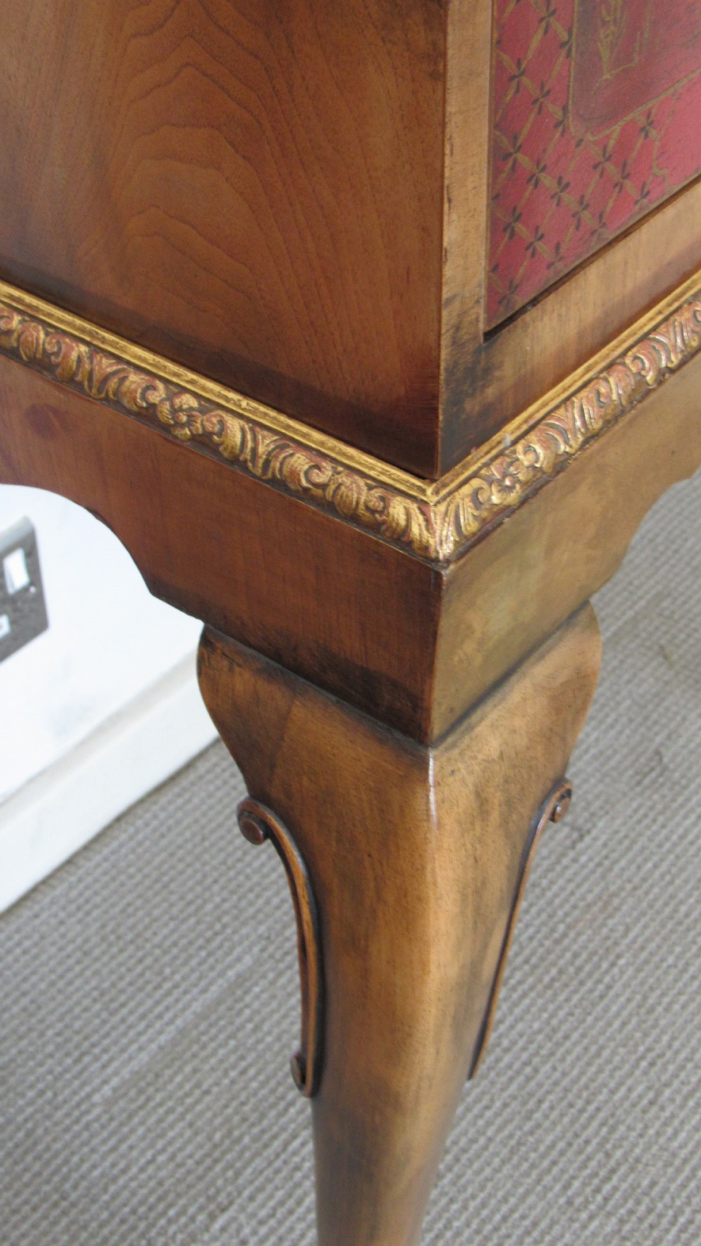 A red lacquered chinoiserie cocktail cabinet decorated with gilt landscapes and figures, featuring ornate brass hinges and set on a carved timber stand with cabriole legs. View XVIII